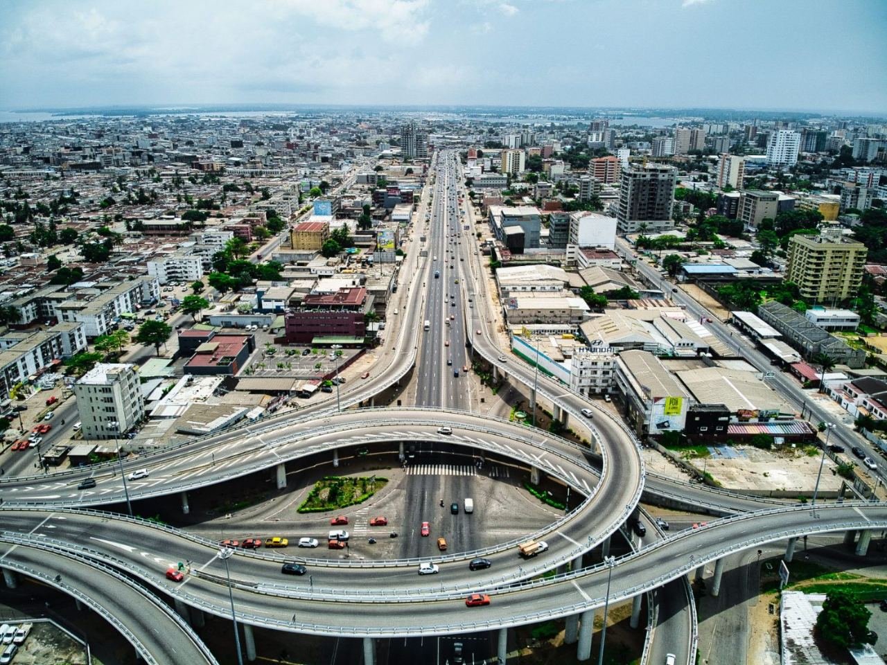Luftbild von Abidjan mit Autobahnkreuz, Hochhäusern und Lagune im Hintergrund