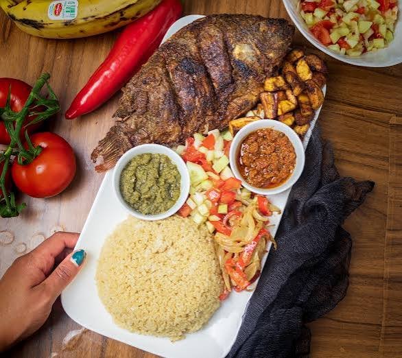Teller mit gegrilltem Fisch, Attiéké, Alloco und Tomatensauce
