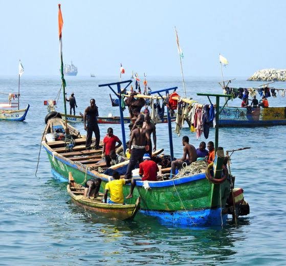 Bemalte Fischerboote mit Besatzung auf ruhigem Wasser
