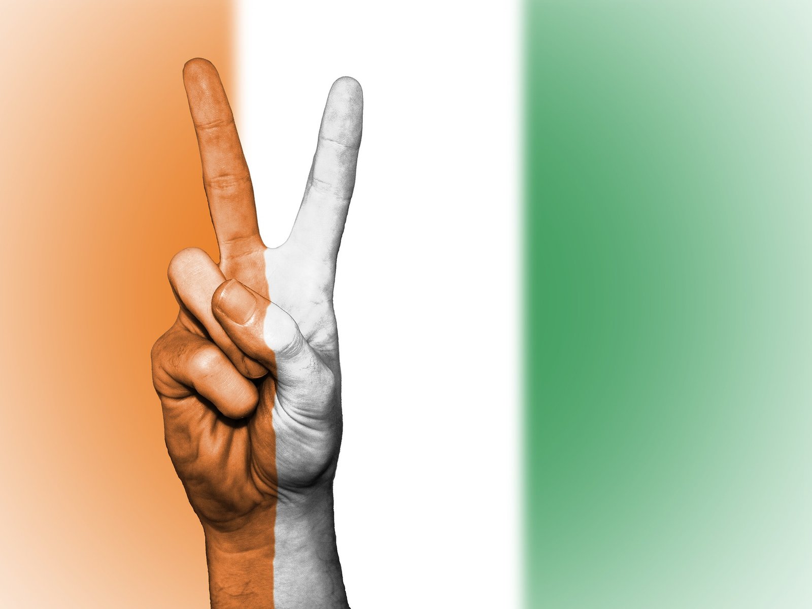Hand zeigt das Friedenszeichen, in den Farben der ivorischen Flagge bemalt