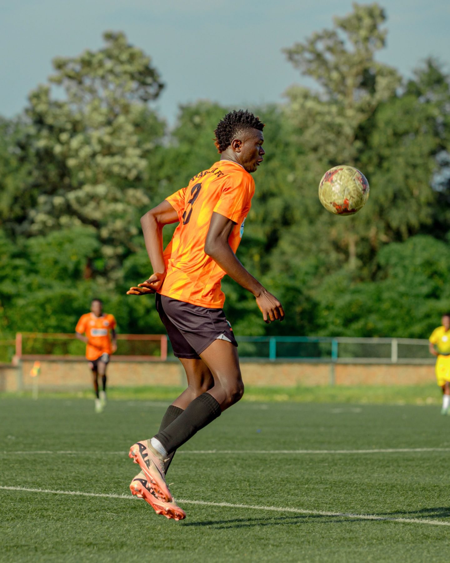 Fußballspieler im orangefarbenen Trikot nimmt den Ball an