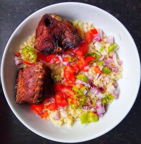 Schale mit Attiéké, gebratenem Fisch, Tomaten, Zwiebeln und Chili