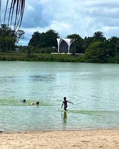 Kinder baden im ruhigen Wasser einer Lagune, Palmen am Ufer