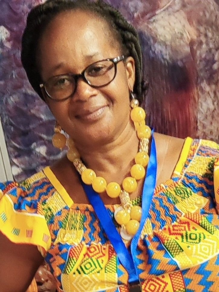 Frau in einer Bluse aus Kente-Stoff mit einer Kette aus großen bernsteinfarbenen Perlen