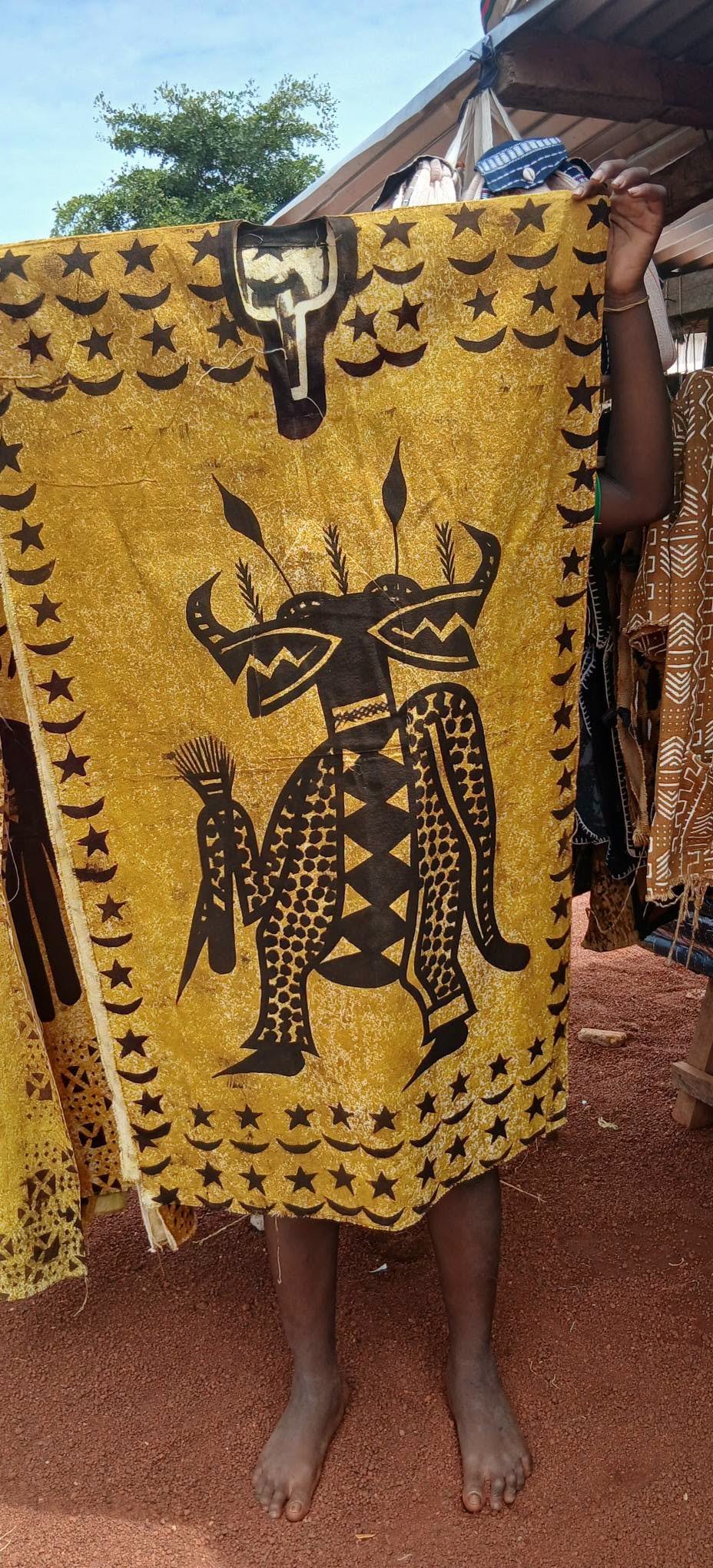 Gelbe Korhogo-Tunika mit aufgemaltem Maskenmotiv und Sternenbordüre