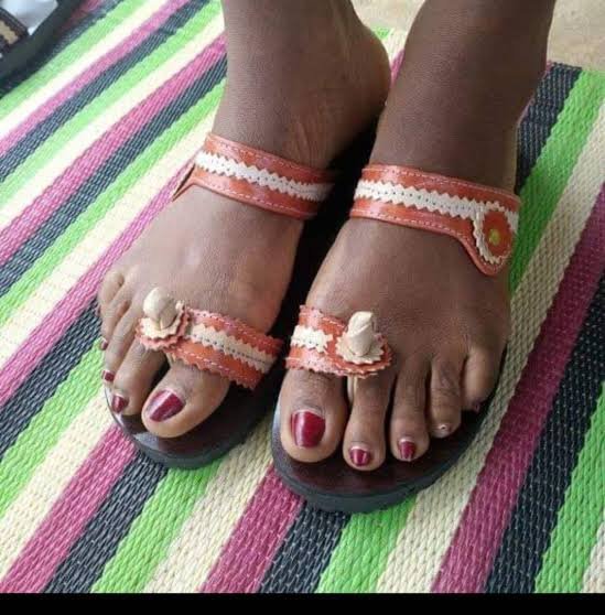 Getragene Ledersandalen mit hellen Flechtriemen auf einer bunten Matte
