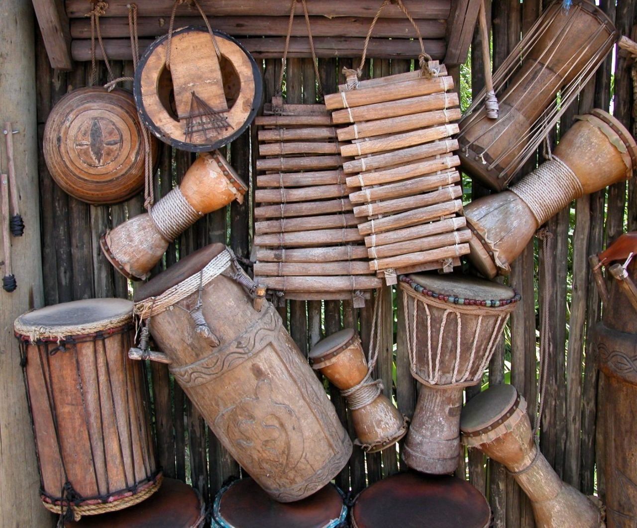 Balafone und Trommeln verschiedener Größe an einer Holzwand