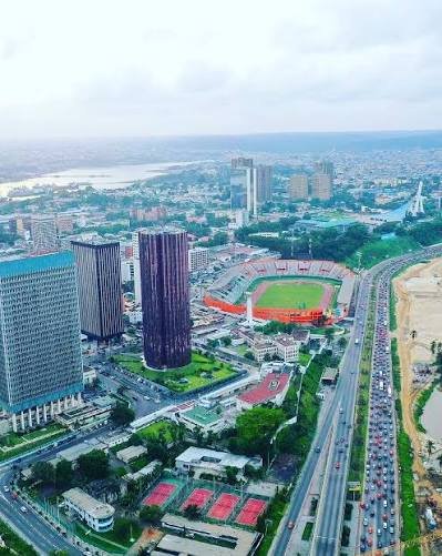 Weites Luftbild von Abidjan mit Hochhäusern, Stadion und Lagune