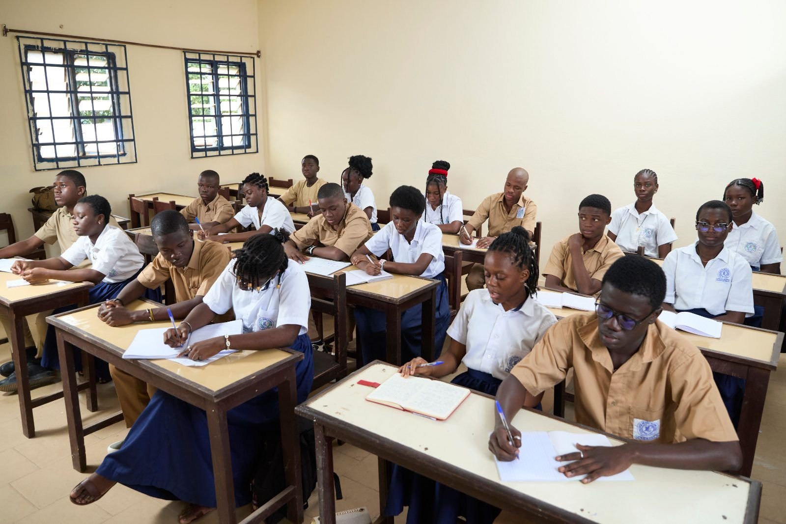 Schülerinnen und Schüler in Schuluniform an ihren Pulten im Klassenzimmer