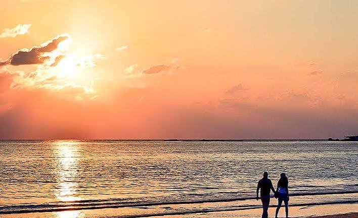 Paar geht bei Sonnenuntergang am Wasser entlang
