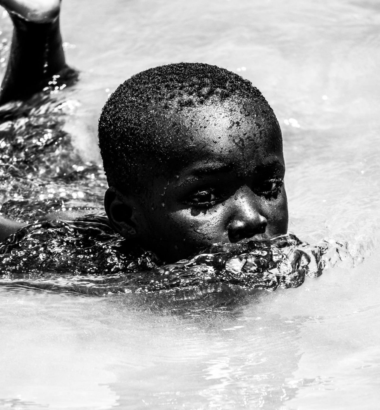 Junge schwimmt, Wassertropfen im Gesicht, Schwarz-Weiß-Aufnahme