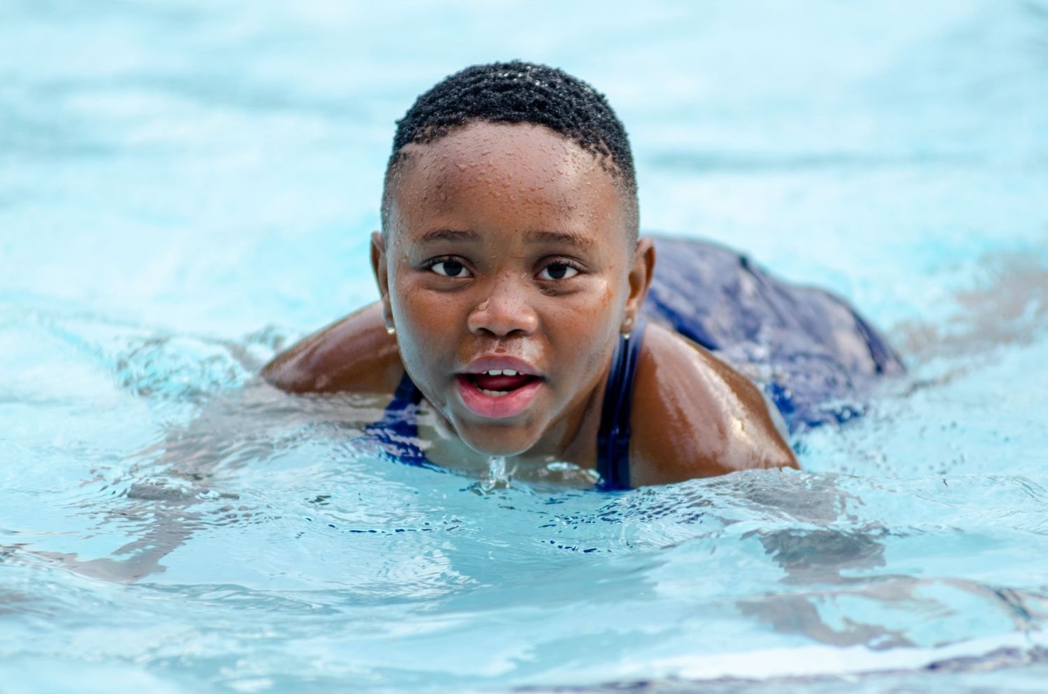 Mädchen schwimmt in einem Becken mit hellblauem Wasser