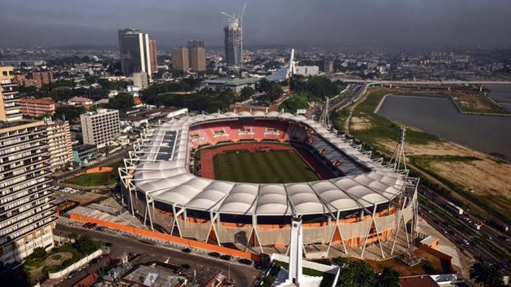 Stadion mit weißem Membrandach zwischen Hochhäusern und Lagune