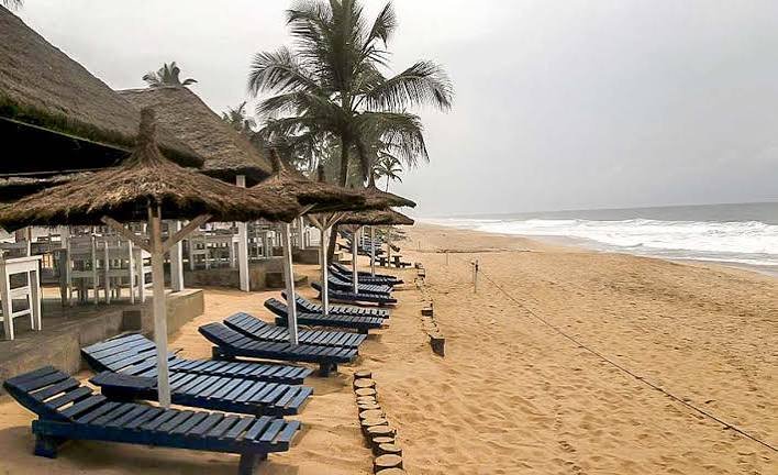 Reihe blauer Liegen unter Strohschirmen am leeren Strand
