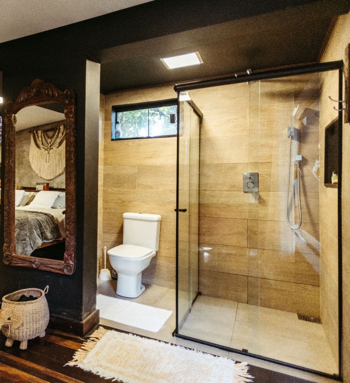 Badezimmer mit Glasdusche, Toilette und großem geschnitztem Holzspiegel