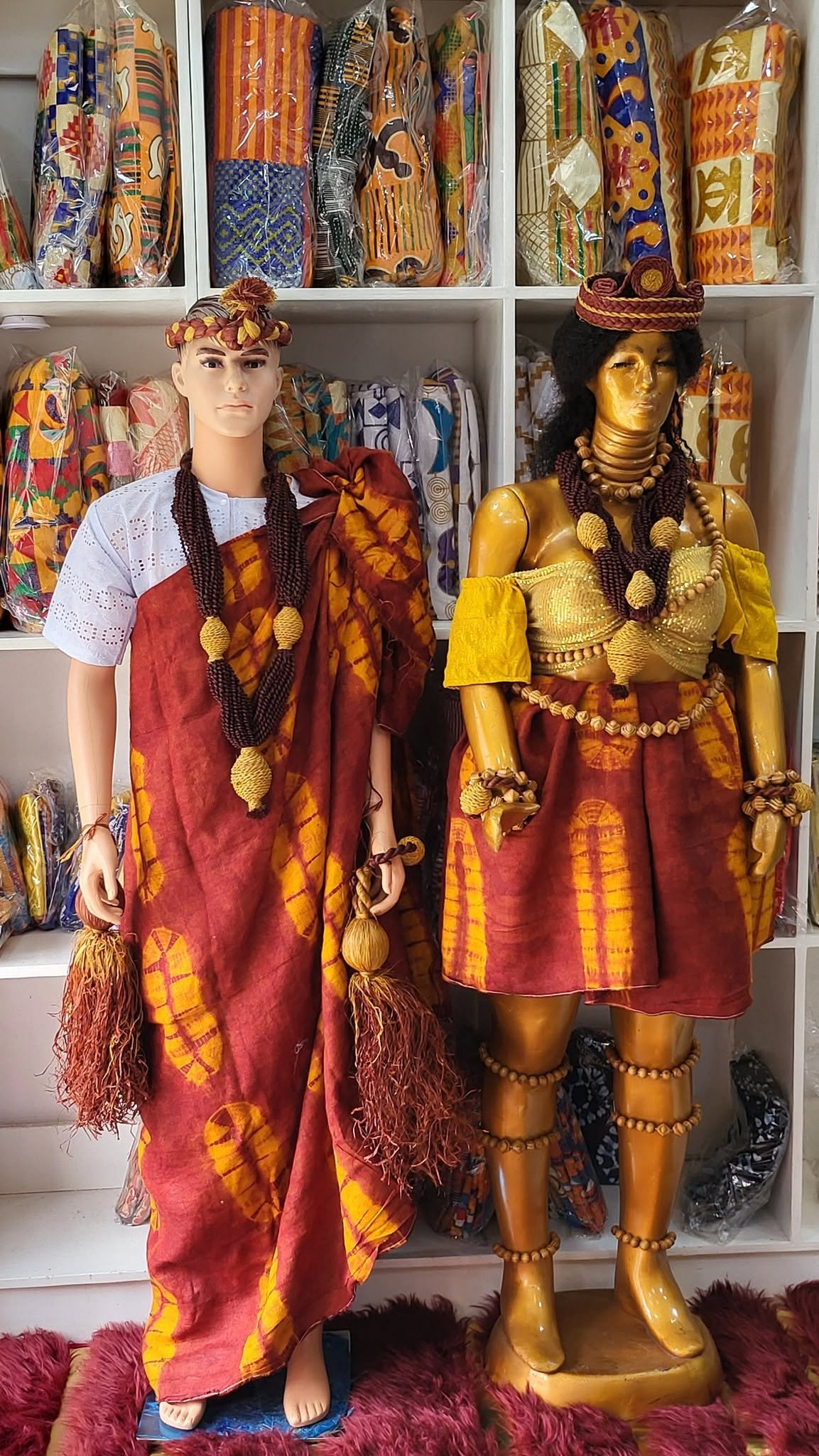 Zwei Schaufensterfiguren in Batik-Zeremonienkleidung in Rot und Gelb